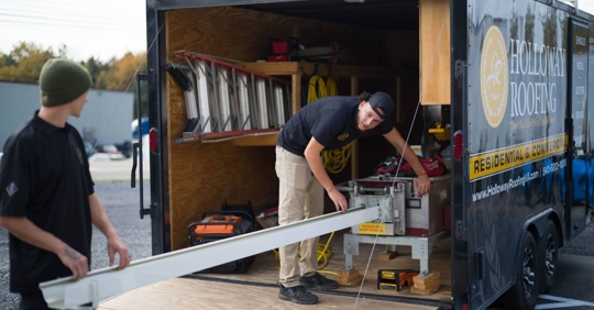 Holloway Roofing team members installing gutters